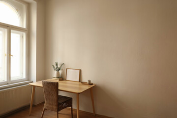 Modern vase with olive branches, old books. Blank horizontal wooden picture frame mockup. Home office table near window. Minimal Scandi boho interior. Cup of tea, coffee. Beige wall background.
