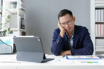 Stressed asian businessman having problem working with digital tablet in office