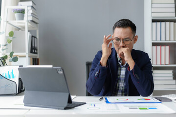 Stressed asian businessman touching his head while working