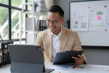 Asian businessman smiling while having video call using tablet in office