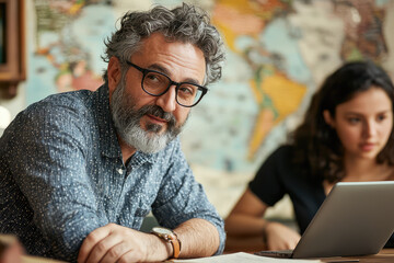 A professor leading study abroad program engages with students in vibrant classroom setting, surrounded by world map. His thoughtful expression reflects dedication to education and cultural exchange
