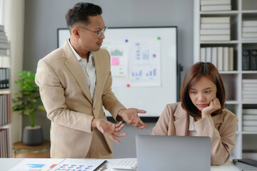 Asian businessman scolding intern for bad results on laptop