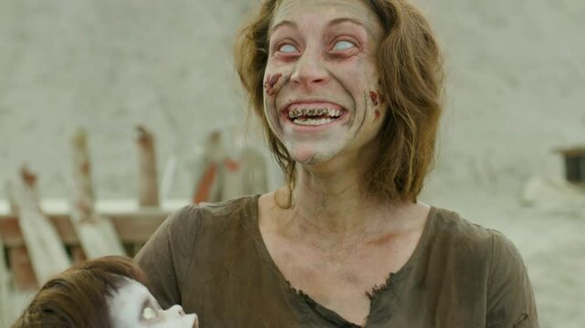 Zombie woman catching scary doll and smiling