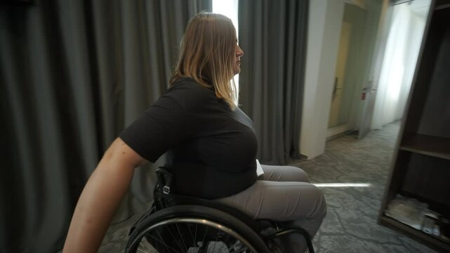 A woman in a wheelchair navigates through a hotel room, highlighting accessible accommodations and inclusive design. The image emphasizes mobility, independence, and modern hospitality infrastructure.