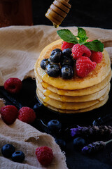 pancakes with berries and honey on dark background