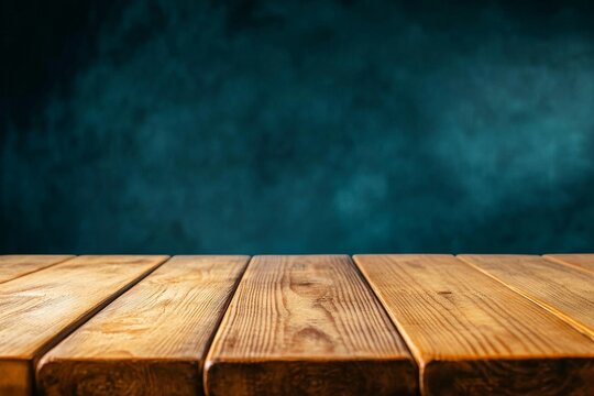 An empty wooden table with a rustic wood grain texture sits atop a textured teal chalkboard background, creating a visually appealing and versatile backdrop for product displays, food photography, or 