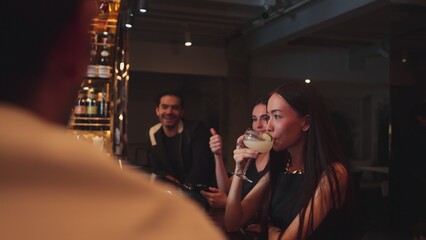 Friends talking while waiting Margarita cocktail savoring sour tasty drink drinking with couple at luxurious counter bar creating happiness moment meeting Friday night at vibrant nightclub. Vinosity.