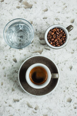 A cup of espresso, coffee beans and glass of water