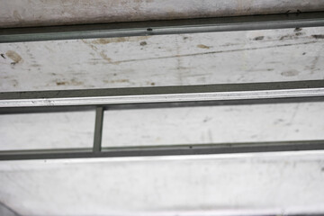 Ceiling frame made of metal profile for suspended ceiling indoors in unfinished renovation room. Installing plasterboard rails. Aluminium structure. Carrying out repairs, improving housing conditions