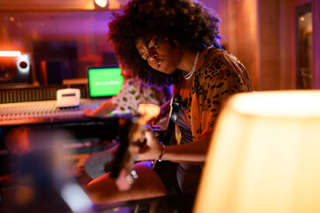 Talented female diverse bass player playing a bass guitar at studio.