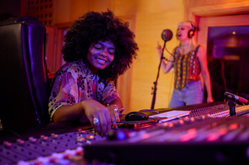 Hispanic latino female sound engineer working with a singer in her studio