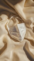 White surgical mask on beige fabric in sunlight, minimalist health and hygiene concept