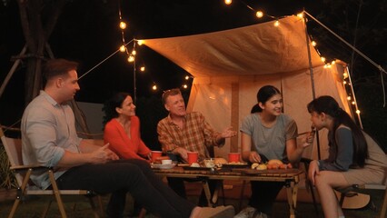 Family gather for holiday celebration in garden. Family member gather have dinner. Outdoor camping activity to relax with food and spend time with younger generation cross generation gap. Divergence.
