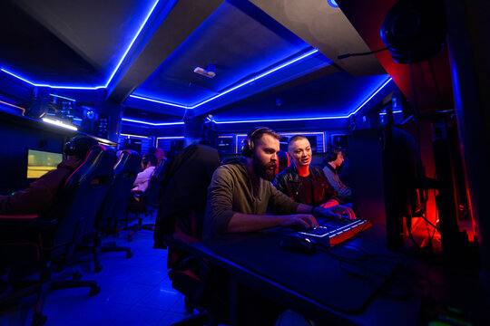 Small group of gaming buddies having lan party in neon lit cybercafe.