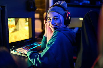 Gamer girl playing a game while looking over shoulder at camera.