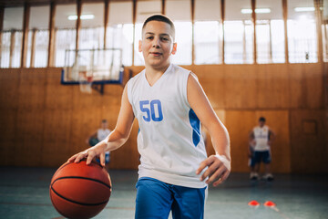 Kid practicing basketball in a sunny gym