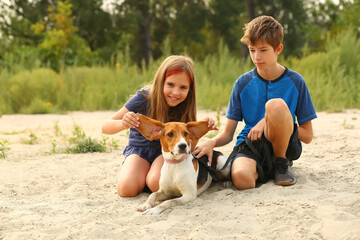 Children walking their estonian hound pet on the beach