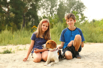 Fototapeta premium Children walking their estonian hound pet on the beach