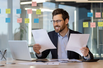 Businessman in formal suit working with documents at desk in modern office. Smiling professional...