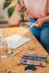 Close up of creative painter's hands mixing paint on palette at atelier