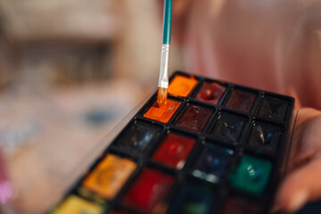 Close up of colorful palette and paintbrush mixing colors.