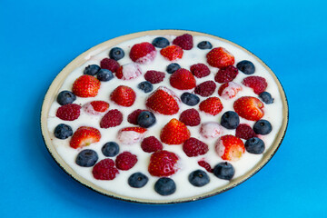 In a plate with freshly whipped cream juicy berries strawberries raspberries