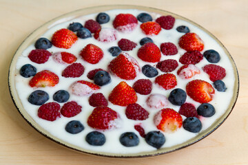 In a plate with whipped cream, strawberries, raspberries and blueberries