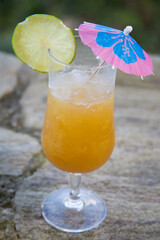 Tropical cocktail standing on stone with lime and umbrella