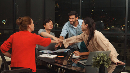 Businesspeople putting hands together and clapping hands to celebrate successful project at modern office with night city view. Group of manager with stacks of hands. Teamwork, trust. Tracery