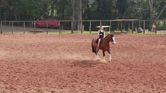 Mulher andando de cavalo em arena de treinos 