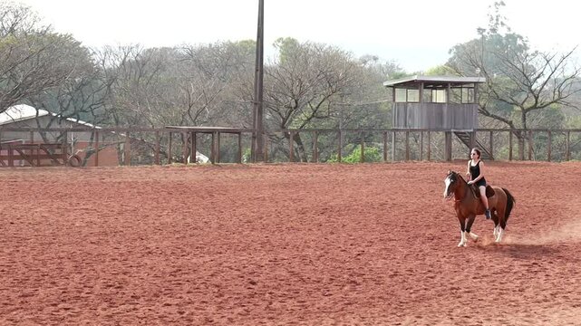Mulher andando de cavalo em arena de treinos 