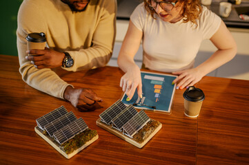 Close up of interracial staff working with solar panels and paperwork.
