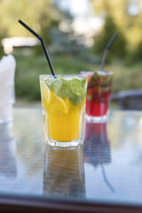 Two drinks on a table, one is a yellow drink with a lime wedge in it