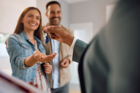 Close up of real estate agent giving house keys to happy couple.