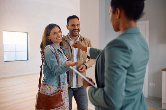 Happy couple receiving keys of their new house from real estate agent.