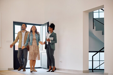 Excited couple entering in new house while meeting with their real estate agent. Copy space.