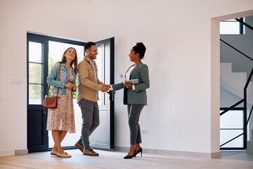 Happy couple meeting with real estate agent while buying new house.
