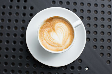 Simple serving of cappuccino coffee with heart shaped floral design.
