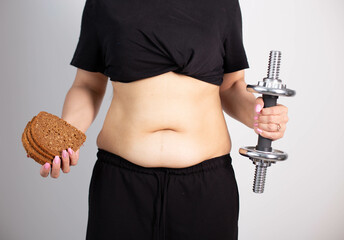 Woman cropped torso with sagging and bloated belly on grey background.