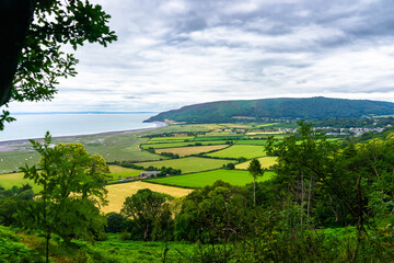 Landscape of a patchwork of fields separated by hedgerows leading down to tidal wetlands and the...