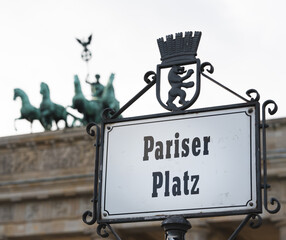 A street sign for Pariser Platz at Brandenburg Gate (Brandenburger Tor) in Berlin, Germany. The gate is visible in the background.