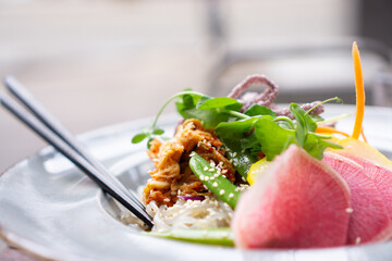 Healthy vegan dish with noodles, beans, greens, sliced red onion, and textured protein.