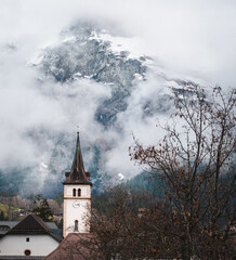 A clock tower beneath the clouds in Lauterbrunnen, Switzerland. The mountains are in the background.