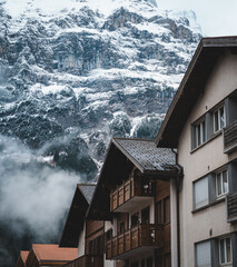 A line of old wooden houses under the snowy winter mountains in Grindelwald, Switzerland.