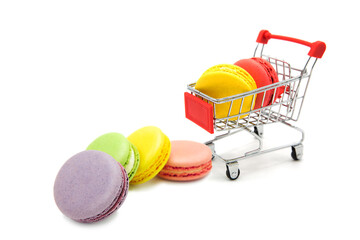 Shopping supermarket cart with colorful varied assortment macarons cookies whole and in a heap...