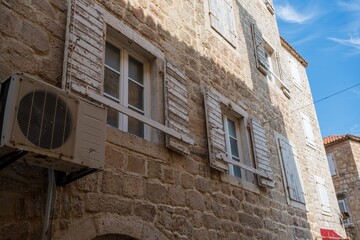 Old stone building with weathered shutters and AC unit