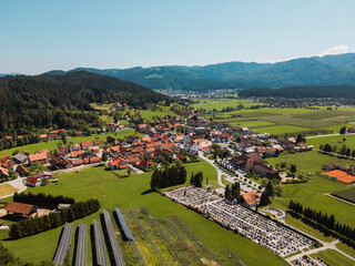 Aerial view of a picturesque village surrounded by lush green fields and mountains. The village...