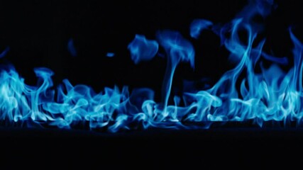 Gas burns with a bright blue flame. Blue fire is burning. Slow-motion video of bright blue flames against a black background. A wall of real fire with an abstract background. Super-slow motion video