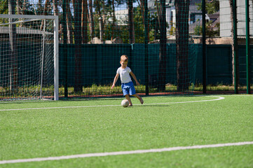 4 year old boy playing with a ball on a football field