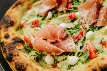 Gourmet pizza with prosciutto, arugula, mozzarella, and fresh tomatoes - perfect Italian cuisine